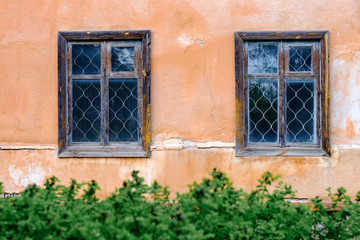Fototapeta na wymiar two Windows glazed with bars on the old beige wall with cracks
