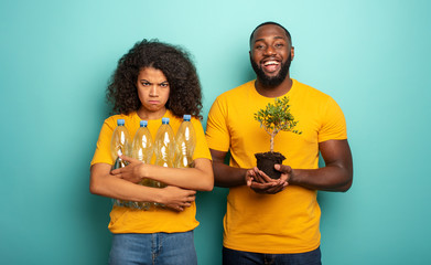 Pollution versus nature. Girl unhappy with plastic garbage and boy happy with a small tree. Save...