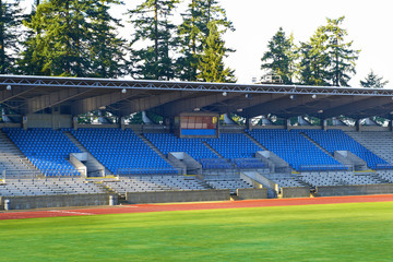 Empty football stadium with green soccer field and blue seats