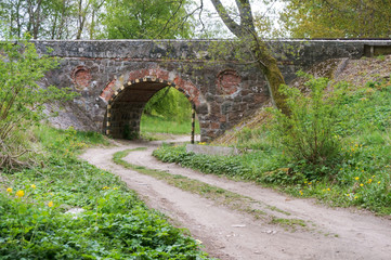 Fototapeta na wymiar Arched bridge over a country road. Arched passage under the railway.