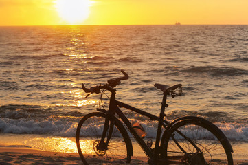 Bike and sunset by the sea. Black bike by the sea.