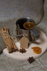 Brewed tea bag in a metal mug. A slice of dried mandarin floats in it. Nearby peeled mandarin,...