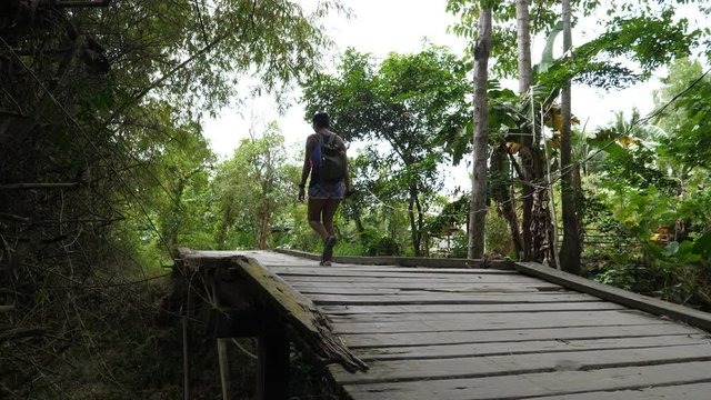 Asian woman walks over wooden bridge in country side of Philipinnes