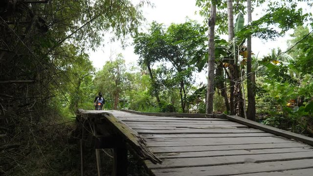Motor drives over wooden bridge in country side of Philipinnes