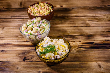 Set of festive mayonnaise salads on wooden table