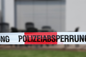 Absperrband mit der Aufschrift Polizeiabsperrung, im Hintergrund ein Wohnhaus