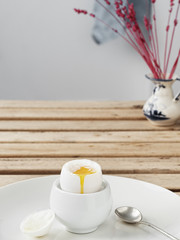 Soft-boiled egg, white egg on a wooden brown table. White ceramic plate with soft-boiled egg. Morning, healthy breakfast. Close-up. Copy space