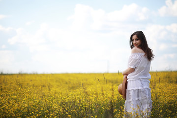 Naklejka na ściany i meble Pregnant woman in a dress in a field of flowers