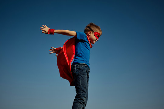 Super hero child (boy) against blue sky