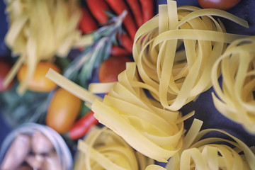 Pasta on the table with spices and vegetables. Noodles with vegetables for cooking on a black stone...
