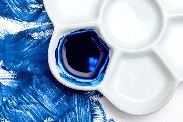 White ceramic palette and blue watercolor paint. Color 2020.  Blue paint strokes.