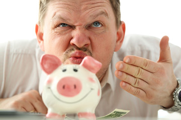 Funny businessman smelling scent of money from piggybank
