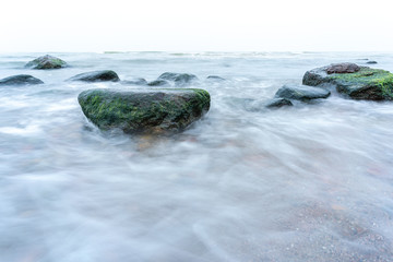 A view of the rocky beach in Miedzyzdroje. Baltic sea. Stones into the water. Blurry effect with long exposure.