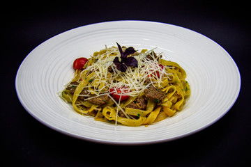 Pasta with beef and cherry tomatoes on black background