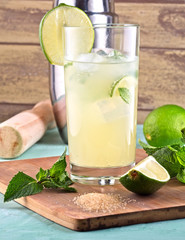 Mojito cocktail decorated with lime, mint leaves, ice cubes and silver shaker