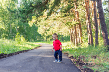 Obraz premium portrait of smiling little boy on the street. cute cheerful baby walking in the Park. happy child