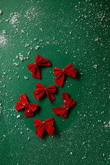 Red bows on green background top view