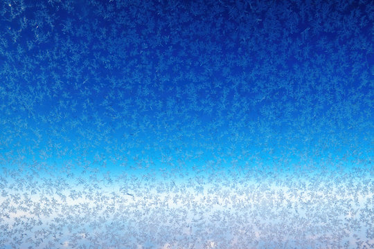 Frozen porthole glass and snowflakes on a blue background. Abstract backdrop