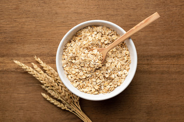 Oat flakes, grains, rolled oats in bowl on wooden table background, top view