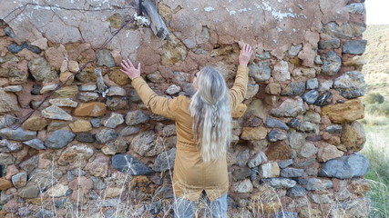 Eine Frau betrachtet und betastet die Wand einer alten Ruine © Gaby Recker