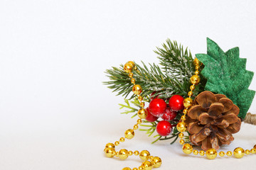 Christmas decorations and toys: berries and leaves of holly, snowy cone and golden beads on a white background. Free space for an inscription