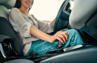 Young beautiful woman is choosing a new vehicle in car dealership. Lady in a car salon. Woman...