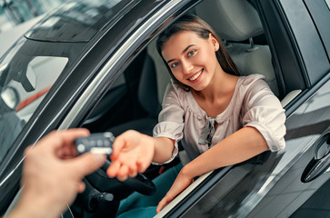 Young woman receiving the keys of her new car. Woman buying the car.