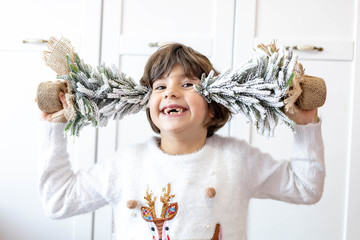 Cute, little girl posing with two decorative Christmas trees. Holiday time