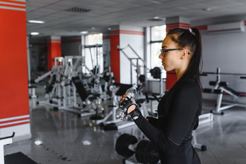 Young woman drinking water after exercising. Fitness gym.