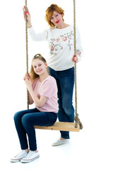 Mom and daughter swinging on a swing.
