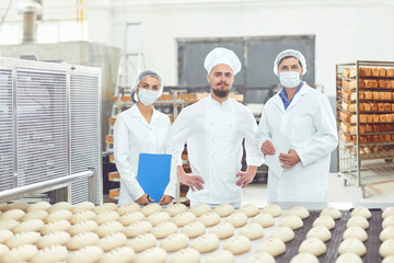 Technologist and baker inspect the bread production line at the bakery
