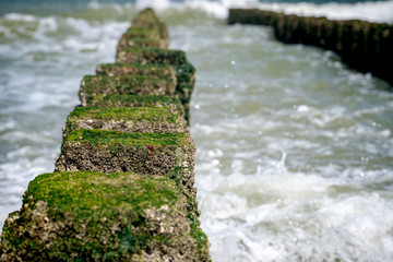 Close up beach poles splashed by water at the sea coast