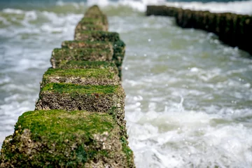 Foto op Plexiglas Close up beach poles splashed by water at the sea coast © fotografiecor