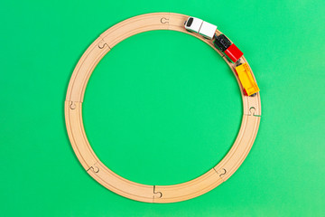 Toy train moves on round wooden railways on light green background. Top view