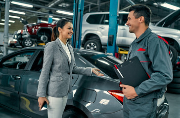Beautiful businesswoman and auto service mechanic are discussing the work. Car repair and...