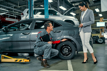 Beautiful businesswoman and auto service mechanic are discussing the work. Car repair and...