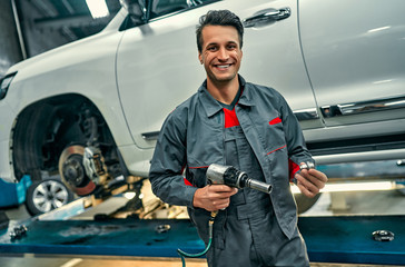 Handsome mechanic in uniform is working in auto service. Car repair and maintenance....