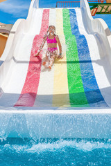 Child on rainbow coloured water slide.