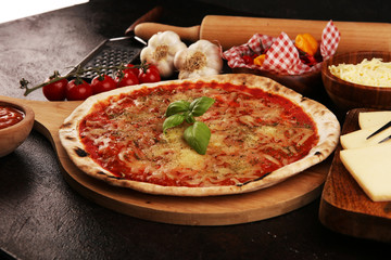 Pizza with tomatoes, mozzarella cheese, basil. Delicious italian pizza on wooden pizza board.
