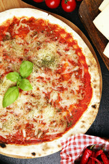 Pizza with tomatoes, mozzarella cheese, basil. Delicious italian pizza on wooden pizza board.