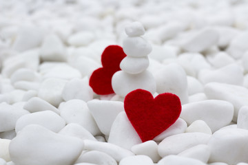 red hearts on Valentine's day are hiding behind white stones on a bright background