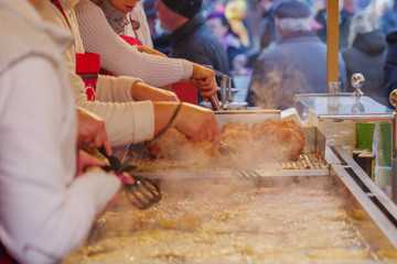 View of deep fried Reibekuchen, Kartoffelpuffer, Potato Pancakes on boiling oil and deep fryer at front of stall at Weihnachtsmarkt, Christmas Market, in Düsseldorf, Germany.