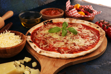 Pizza with tomatoes, mozzarella cheese, basil. Delicious italian pizza on wooden pizza board.