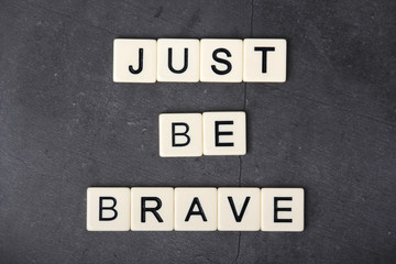 A motivational quote Just be brave formed with tile letters	