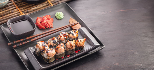 Sushi rolls with shrimp and cheese on dark table with space for text
