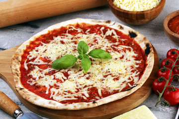 Pizza with tomatoes, mozzarella cheese, basil. Delicious italian pizza on wooden pizza board.