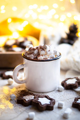 Comforting Christmas food, mug of hot cocoa with marshmallow and cookies with cozy lights