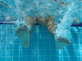 Legs of children in pool underwater