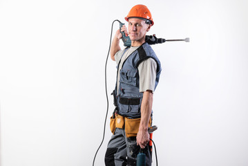 A builder with a hammer drill on his shoulder, in a helmet, smiles.