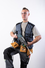 Builder with a drill in his hands, in safety glasses.